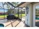 Screened-in porch featuring an outdoor shower, leading to a lush backyard, and outdoor grill at 8170 Casa De Meadows Dr, Englewood, FL 34224