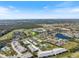 Aerial view of residential community with mature trees, lake, golf course and a green pushpin at 944 Capri Isles Blvd # 103, Venice, FL 34292