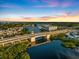 Dramatic aerial view of a coastal city features a bridge over a waterway, a marina, and stunning sunset colors at 944 Capri Isles Blvd # 103, Venice, FL 34292