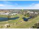 Aerial view of residential neighborhood with a green pushpin, lake, golf course and lush trees at 944 Capri Isles Blvd # 103, Venice, FL 34292