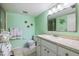 Green bathroom with fish decorations, vanity, toilet and a shower with glass doors at 944 Capri Isles Blvd # 103, Venice, FL 34292