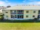 Rear view of the two-story condo building overlooking a grassy lawn with screened in lanai at 944 Capri Isles Blvd # 103, Venice, FL 34292