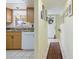 Bright hallway and kitchen featuring tile floors, white appliances, and natural wood cabinets at 944 Capri Isles Blvd # 103, Venice, FL 34292