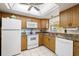 Bright kitchen with wooden cabinets, white appliances, and tile flooring for easy maintenance at 944 Capri Isles Blvd # 103, Venice, FL 34292