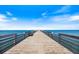 Symmetrical view of a wooden pier stretching into the ocean with calming blue waters and clear skies at 944 Capri Isles Blvd # 103, Venice, FL 34292