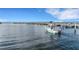Scenic view of a waterfront with a boat navigating through calm waters near a wooden pier and distant shoreline at 1 Colony Point Dr # 11A, Punta Gorda, FL 33950
