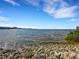 Scenic waterfront view with calm water and a rocky shoreline under a clear blue sky, offering a tranquil escape at 1 Colony Point Dr # 11A, Punta Gorda, FL 33950