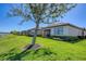 Manicured backyard with a mature tree offering shade and scenic views of a tranquil lake at 10412 Crooked Creek Dr, Venice, FL 34293