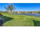Tranquil backyard view overlooking a serene lake surrounded by lush green grass and sky at 10412 Crooked Creek Dr, Venice, FL 34293