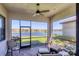 Screened-in lanai overlooking a serene lake view with comfortable seating and ceiling fan at 10412 Crooked Creek Dr, Venice, FL 34293