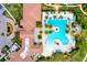 Aerial view of a luxury community pool with palm trees, lounge chairs, and the clubhouse with dining areas at 10742 Ironbridge Dr, Venice, FL 34293