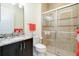 Well-lit bathroom featuring granite countertops, a dark wood vanity, and a glass-enclosed shower with tiled walls at 10742 Ironbridge Dr, Venice, FL 34293