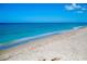 Serene beachfront view with white sand and calm turquoise water under a clear blue sky at 10742 Ironbridge Dr, Venice, FL 34293