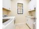 Well-organized laundry room with white cabinets, a window, and a sink with granite countertops next to the new appliances at 10742 Ironbridge Dr, Venice, FL 34293
