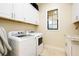 Bright laundry room with front loading washer and dryer, cabinets for storage, and sink with granite countertop at 10742 Ironbridge Dr, Venice, FL 34293