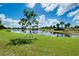 Picturesque pond with a young tree in the foreground reflecting blue skies and fluffy clouds at 10742 Ironbridge Dr, Venice, FL 34293