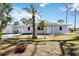 Inviting home exterior with a covered carport, complemented by a palm tree and vibrant landscaping at 1075 Falcon Rd, Venice, FL 34293