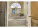 A luxurious tub in a bathroom with a unique architectural window and adjacent shower at 1125 Deardon Dr, Venice, FL 34292