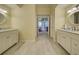 Spacious bathroom with dual vanities and a hallway view, tiled flooring at 1125 Deardon Dr, Venice, FL 34292