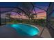 The screened-in pool glows against a vibrant twilight sky, creating a serene backyard oasis at 1125 Deardon Dr, Venice, FL 34292