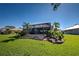 Screened in pool with palm trees and lush landscaping viewed from a large, well-manicured lawn at 1125 Deardon Dr, Venice, FL 34292