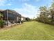 Spacious, grassy backyard features a screened-in lanai with dining, seating, and a grill at 11575 Okaloosa Dr, Venice, FL 34293