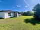 Back exterior view of white home featuring screened in porch and large grassy yard at 12390 Talavera St, North Port, FL 34287