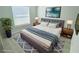 Cozy staged bedroom with soft, neutral colors, a tufted headboard, and a large window at 12390 Talavera St, North Port, FL 34287