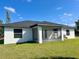 The back of the house, featuring a screened patio, a well-manicured lawn, and white stucco at 12390 Talavera St, North Port, FL 34287