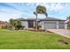 Charming single-story home featuring a well-manicured lawn, palm trees, and a three-car garage at 15688 Melport Cir, Port Charlotte, FL 33981