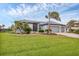Charming single-Gathering home with a well-manicured lawn, mature palm trees, and a two-car garage at 15688 Melport Cir, Port Charlotte, FL 33981