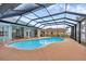 Enclosed pool and deck area featuring a kidney-shaped pool under a screened enclosure at 15688 Melport Cir, Port Charlotte, FL 33981