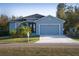 Charming one-story home with a well-manicured lawn, blue paint, and a two-car garage at 177 Ingram Blvd, Rotonda West, FL 33947