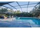 A gorgeous screened-in pool and spa with a sun umbrella and patio furniture at 177 Ingram Blvd, Rotonda West, FL 33947