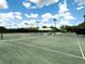 Outdoor tennis court with net and lighting, surrounded by trees and greenery at 1833 Lancashire Dr, Venice, FL 34293