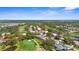 Scenic aerial view of a golf course community with lush landscaping, a pond and sunny skies at 1995 White Feather Ln, Nokomis, FL 34275