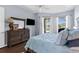Bright bedroom includes a dresser, wall-mounted TV, and view to the screened pool area at 1995 White Feather Ln, Nokomis, FL 34275