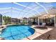 Inviting in-ground pool with a screened enclosure, lush landscaping, and sunny lounging areas at 1995 White Feather Ln, Nokomis, FL 34275