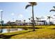 Exterior of stadium with grassy areas, pond, palm trees, and clear skies in this scenic location at 20806 Valprato Ct, Venice, FL 34293