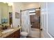 Well-lit bathroom features a granite vanity, decorative shower curtain, and tiled shower with safety bars at 20806 Valprato Ct, Venice, FL 34293
