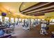 Bright gym with an array of modern fitness equipment, mounted TV screens, and hardwood support beams at 20806 Valprato Ct, Venice, FL 34293
