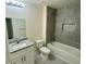 Bright bathroom features a granite countertop, gray-tiled shower, and modern lighting fixture at 2643 Orchard Cir, North Port, FL 34288