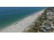 An aerial view showcasing a pristine beach with sunbathers, beach umbrellas, sport court, and waterfront buildings at 2694 Hopwood Rd, North Port, FL 34287