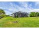 Large, grassy backyard featuring an enclosed lanai and decorative landscaping at 2694 Hopwood Rd, North Port, FL 34287