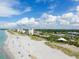 Breathtaking aerial view of a beachfront with white sand, clear water, and nearby condos and a community at 325 Fiesole St, Venice, FL 34285