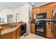 Efficient kitchen features wooden cabinetry, black appliances, granite countertops, and tiled floor at 3691 Parkridge Cir # 201, Sarasota, FL 34243