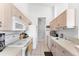 Galley kitchen features neutral countertops and cabinets with white appliances at 4433 Corso Venetia Blvd # C18, Venice, FL 34293
