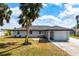 Charming single-story home with a well-manicured lawn, attached garage and a beautiful palm tree at 4740 Payne St, North Port, FL 34287