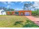 Charming single-story home with an orange exterior, well-manicured lawn, and a red concrete driveway at 491 Conrad Rd, Venice, FL 34293
