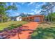 Exterior view of an orange single-story home with an inviting entrance and a long red concrete driveway at 491 Conrad Rd, Venice, FL 34293